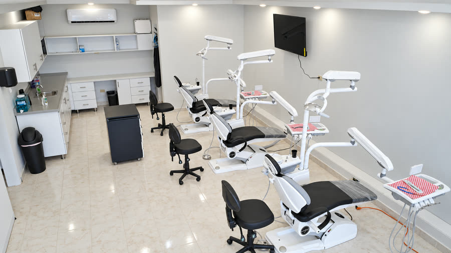 Una sala de tratamiento de Aury Dental Clinic, con tres sillones en fila y gabinetes blancos a lo largo de la pared.