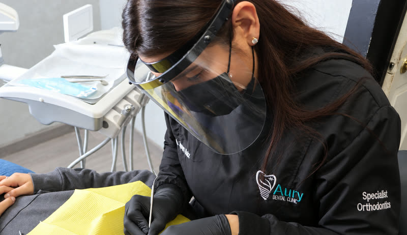 La Dra. Aurora Ruiz atendiendo a un paciente en Aury Dental Clinic, Nuevo Progreso, con careta y guantes.